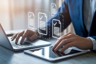 © Din Nasahrudin - stock.adobe.com Foto: Laptop mit zwei Händen und Check-Icons