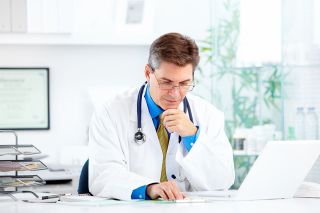 © grinny - stock.adobe.com Foto: Arzt sitzt vor Laptop